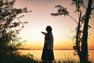 A scenic outdoor shot featuring Ahmad Raza standing thoughtfully by a lake at sunset