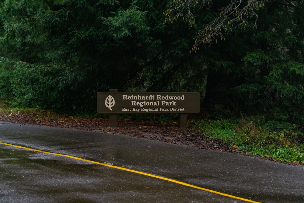 a sign on the side of a road in front of some trees