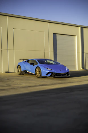 A sleek deep blue lorry parked at a modern warehouse under a clear sky.