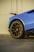 Rear shot of a blue car with a sporty spoiler reflecting the sunset light.