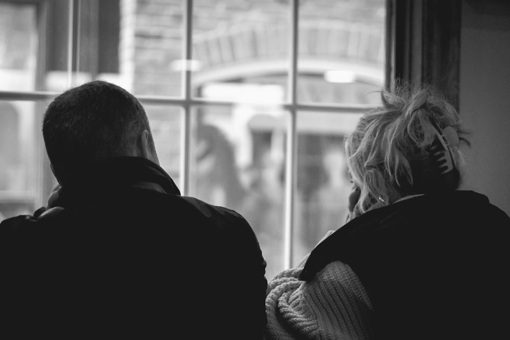 a man and a woman looking out a window