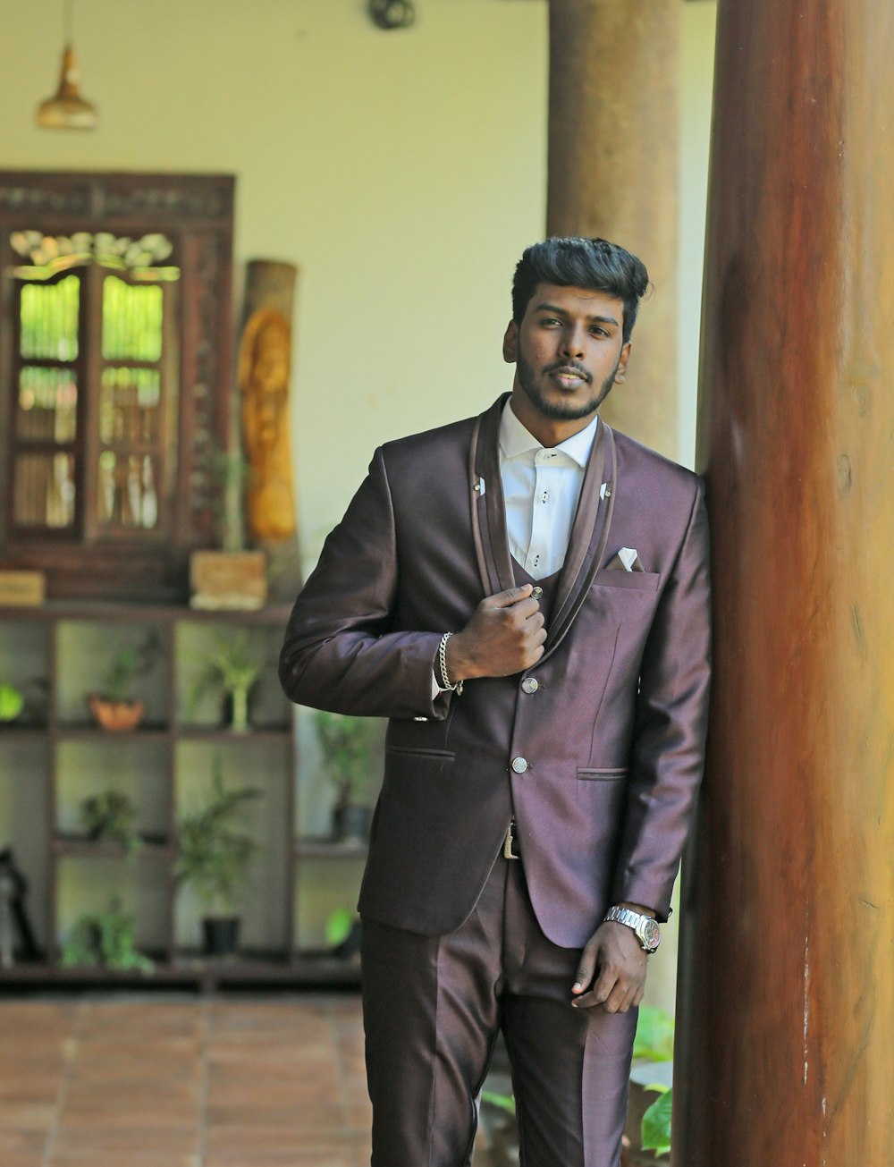 a man in a suit standing next to a pillar