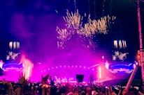 Colorful festival lights illuminating a lively outdoor concert.