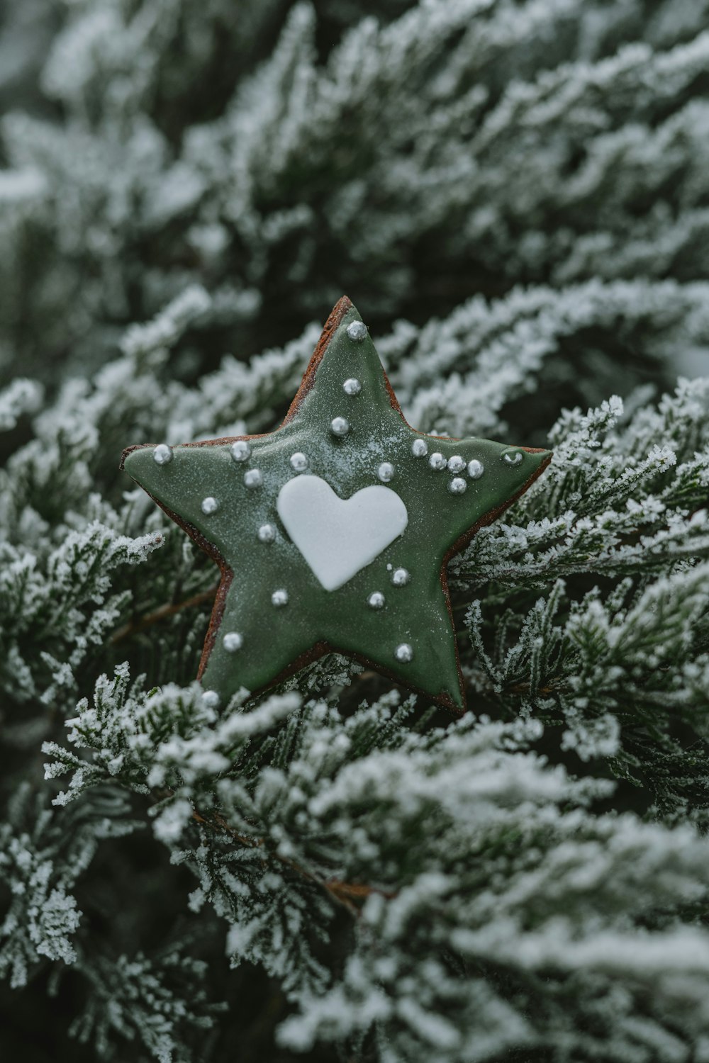 a green star ornament with a white heart on it