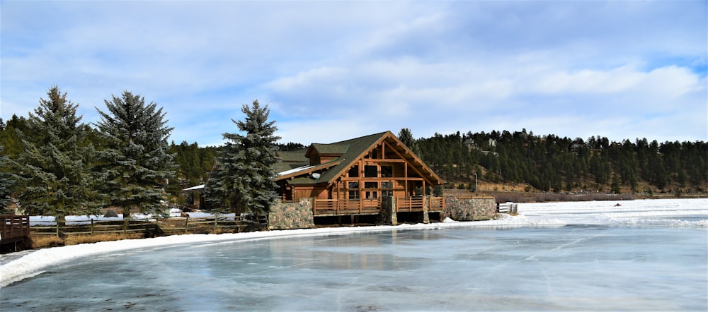 a log cabin sits on the edge of a frozen lake