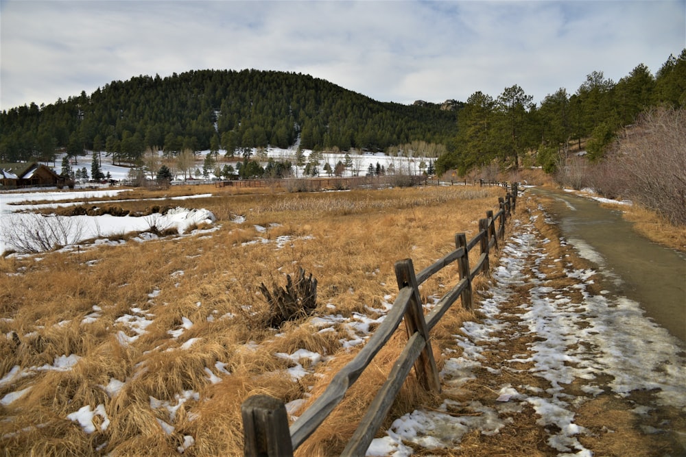 a wooden fence in the middle of a snowy field