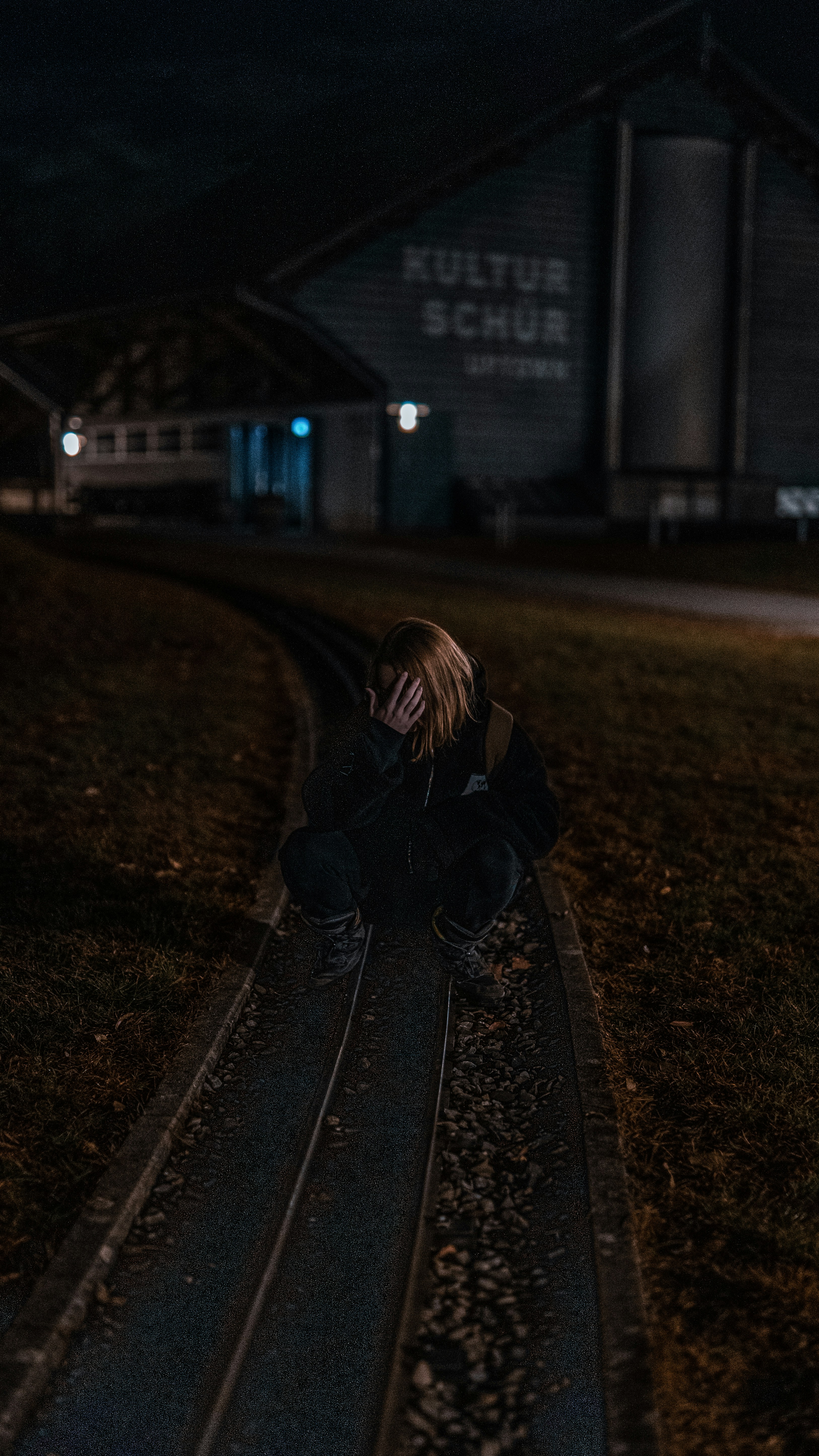 una persona sentada en una vía de tren por la noche
