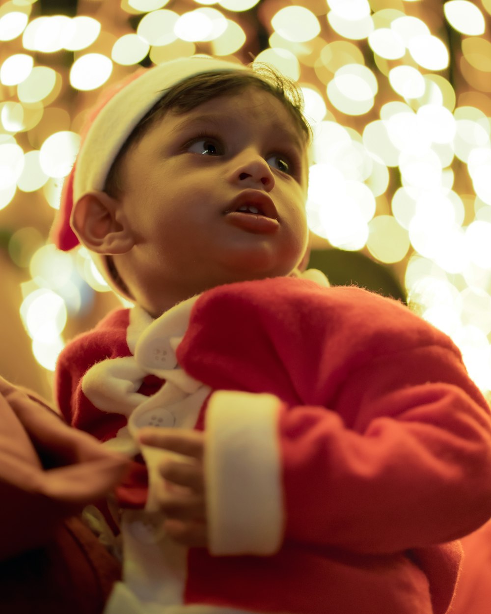 a small child wearing a santa suit and a santa hat