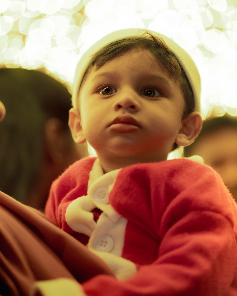 a little boy in a red sweater and a white hat