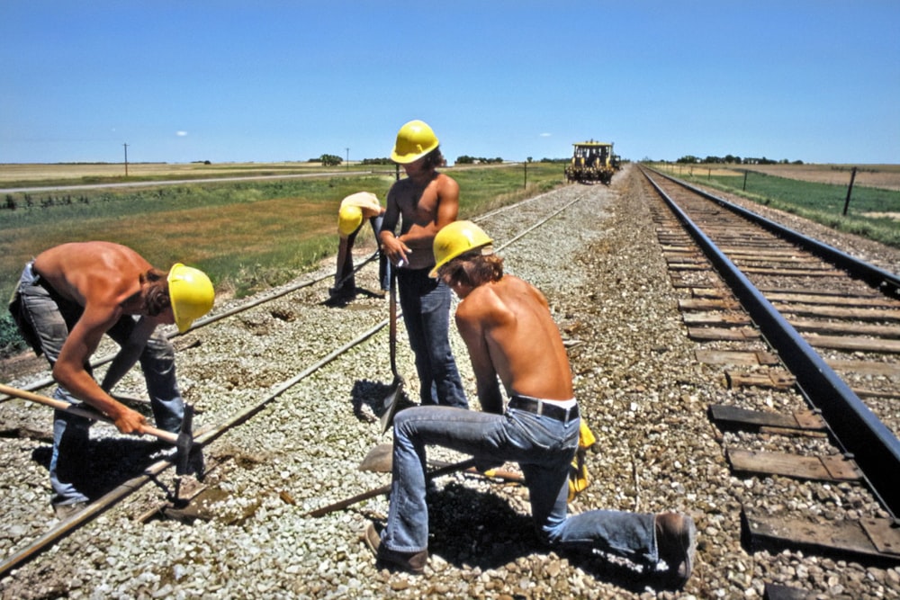 a group of men standing on top of a train track