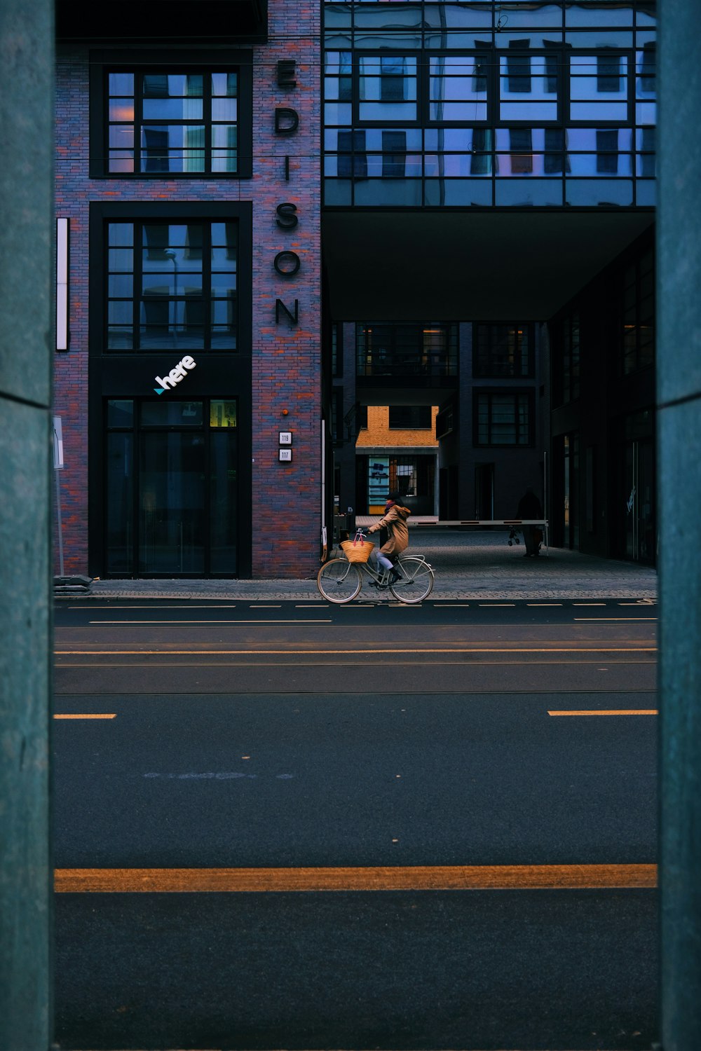 a man riding a bike down a street next to a tall building