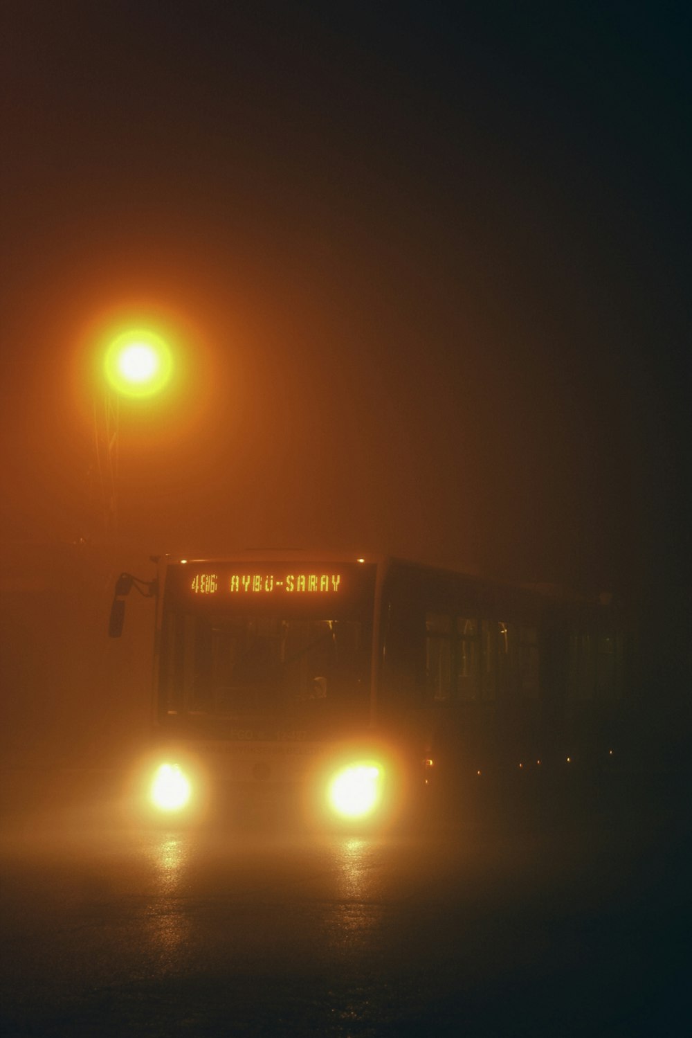 a bus driving down a foggy street at night