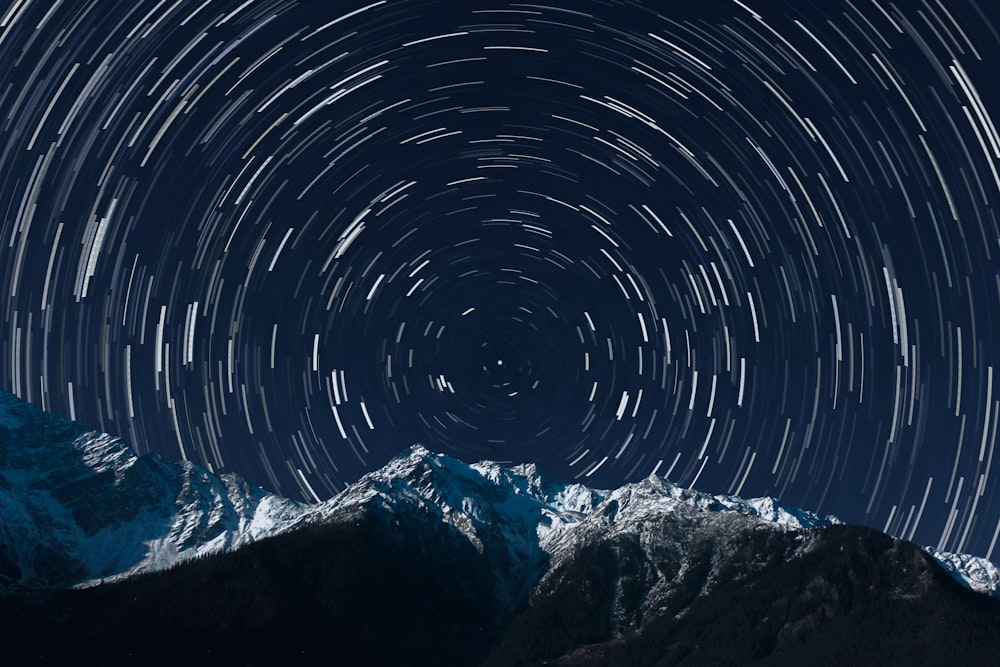 a star trail is seen in the sky above a mountain range