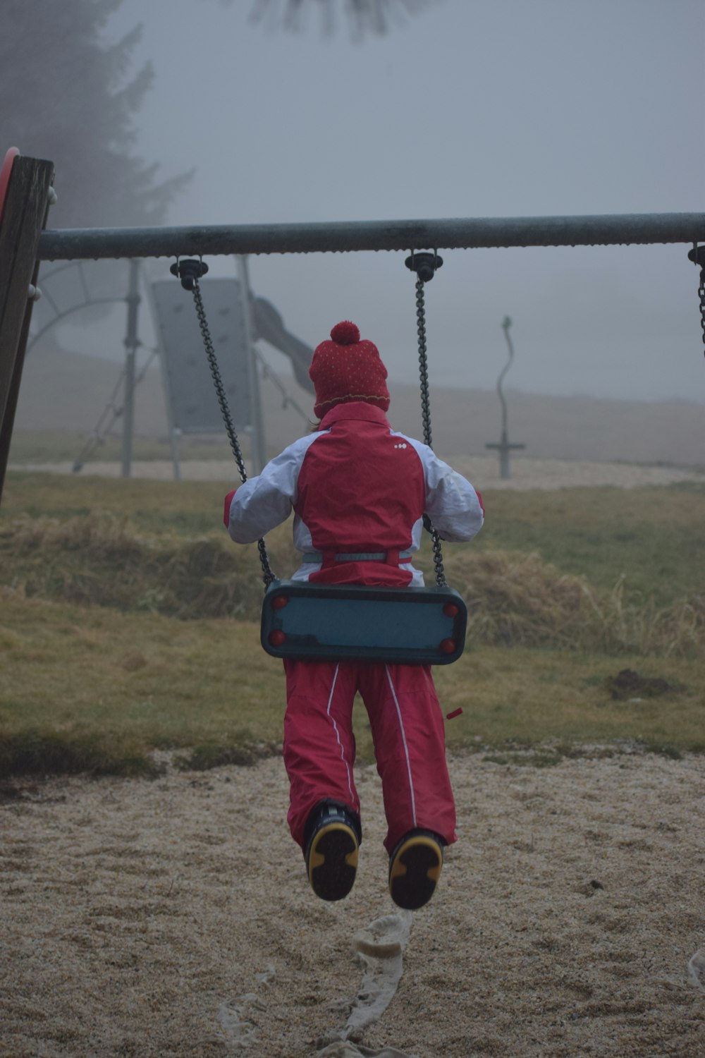 a little girl sitting on a swing in a park