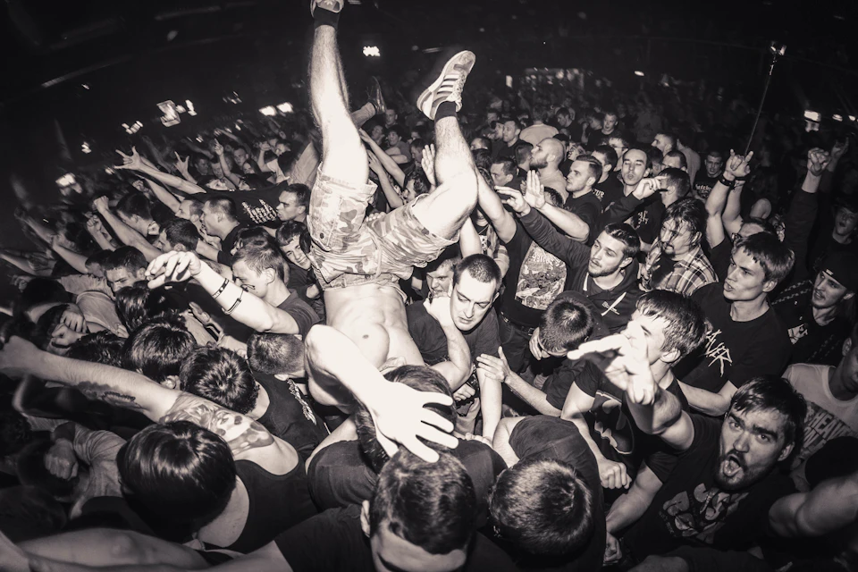 Crowd of people dancing and lifting each other at a lively concert event indoors