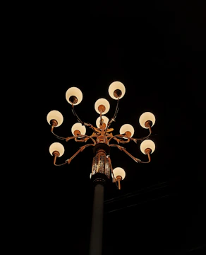 Electrician working at night with portable lighting on a street lamp