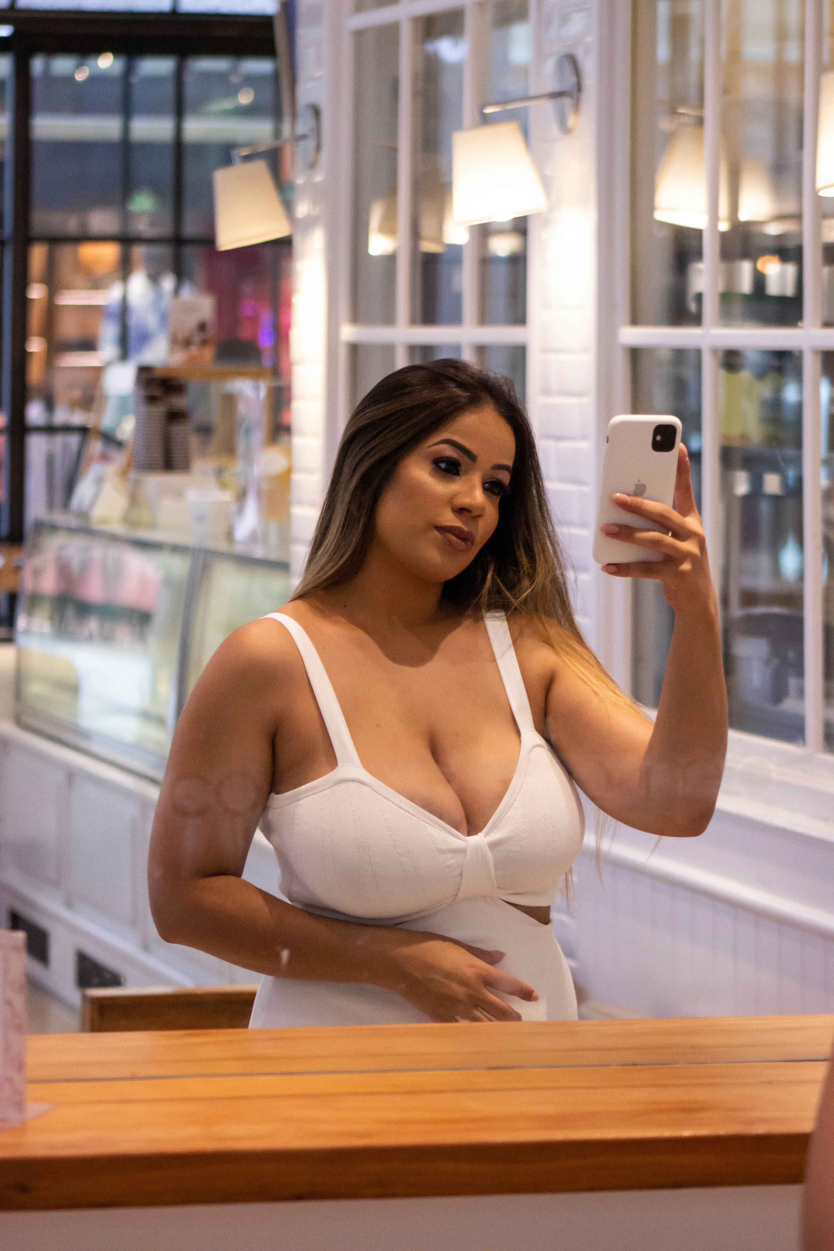 a woman taking a selfie in a white bra