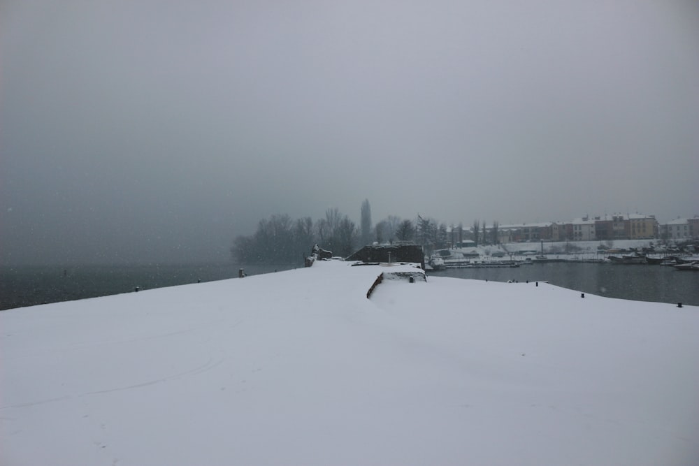 a snow covered hill with a body of water in the background