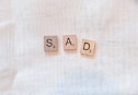 scrabble pieces spelling out sad