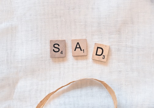 scrabble tiles spelling sad and sad on a white background
