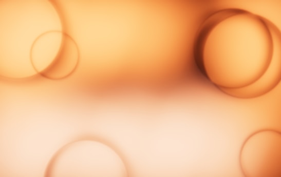 Soft and warm abstract pattern featuring several overlapping, blurred circles in shades of orange and peach. The circles vary in size and are distributed across a smooth gradient background that transitions from a deep orange at the edges to a lighter center.