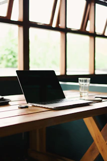 A compact folding table in use with a laptop and a stackable paper tray beside it, bathed in natural light.