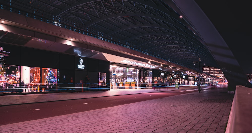 a city street at night with a train station in the background