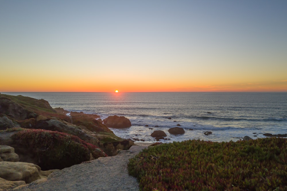 Il sole sta tramontando sull'oceano con le rocce