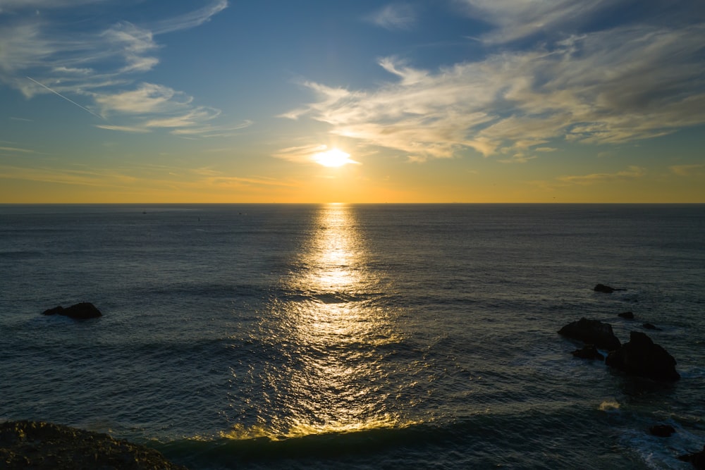 o sol está se pondo sobre o oceano em um dia claro