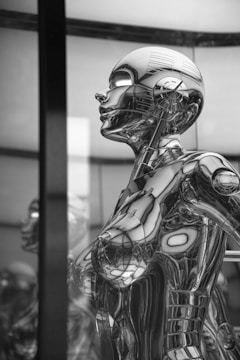 A highly detailed chrome-plated humanoid robot is depicted with intricate designs and reflective surfaces capturing light in various ways. The robot's head and torso are visible, showcasing its futuristic and mechanical aesthetic.