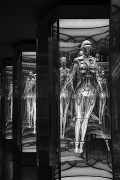 A series of humanoid robotic figures, encased in glass, with intricate mechanical details. The reflections create a tunnel effect, enhancing a futuristic and technological atmosphere.