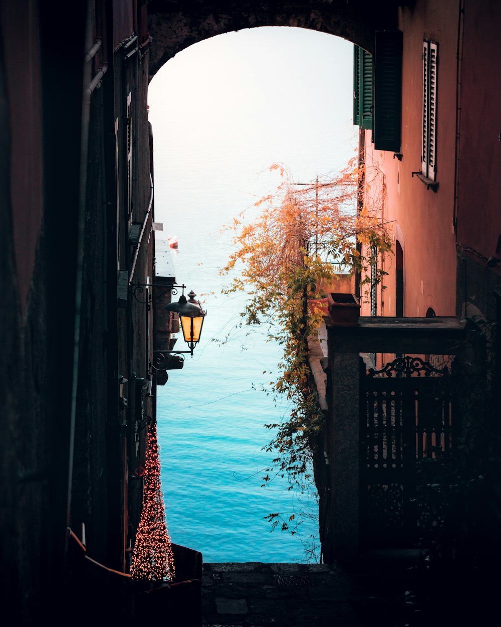 an alley way with a lamp post and a body of water in the distance