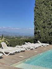 A serene poolside scene with lounge chairs and a clear blue sky.