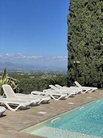 A serene poolside scene with lounge chairs and a clear blue sky.