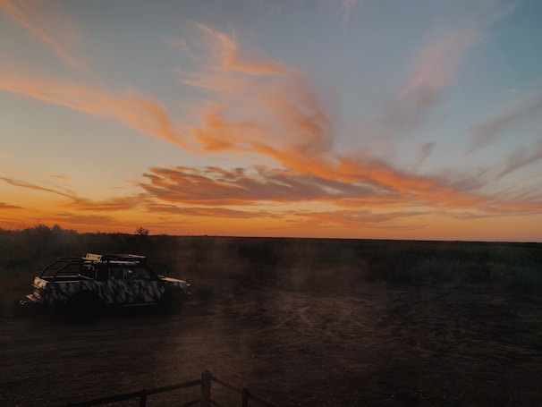 Sunset view over Mount Papandayan with a jeep parked on a rocky path.