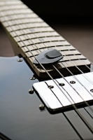 Close-up of a sleek steel guitar neck with polished frets reflecting city lights.