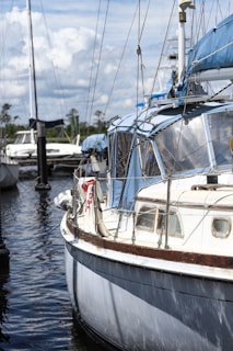 A modern sailboat anchored near a marina with white sails and blue hull