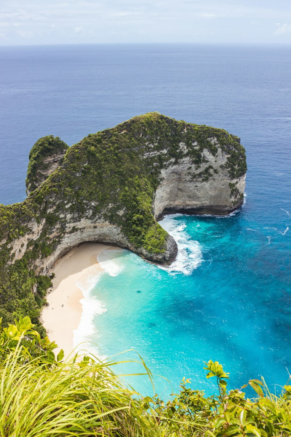 a beach with a large rock formation in the middle of it