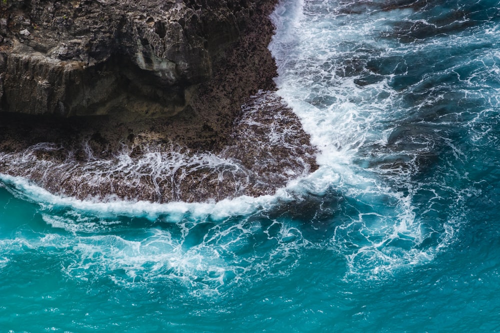 an aerial view of the ocean with waves crashing on the rocks