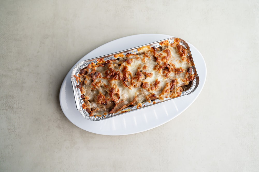a white plate topped with a lasagna covered in cheese