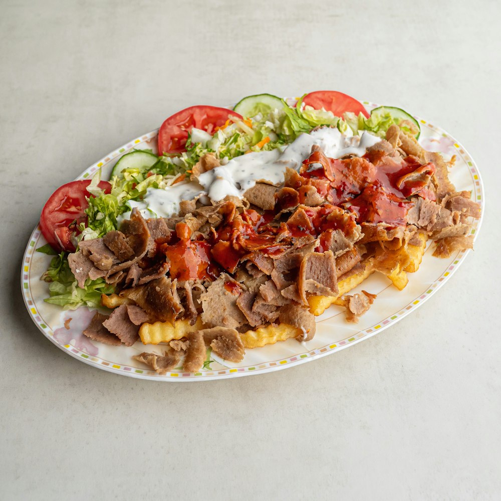 a plate of food with meat, cheese, tomatoes and lettuce