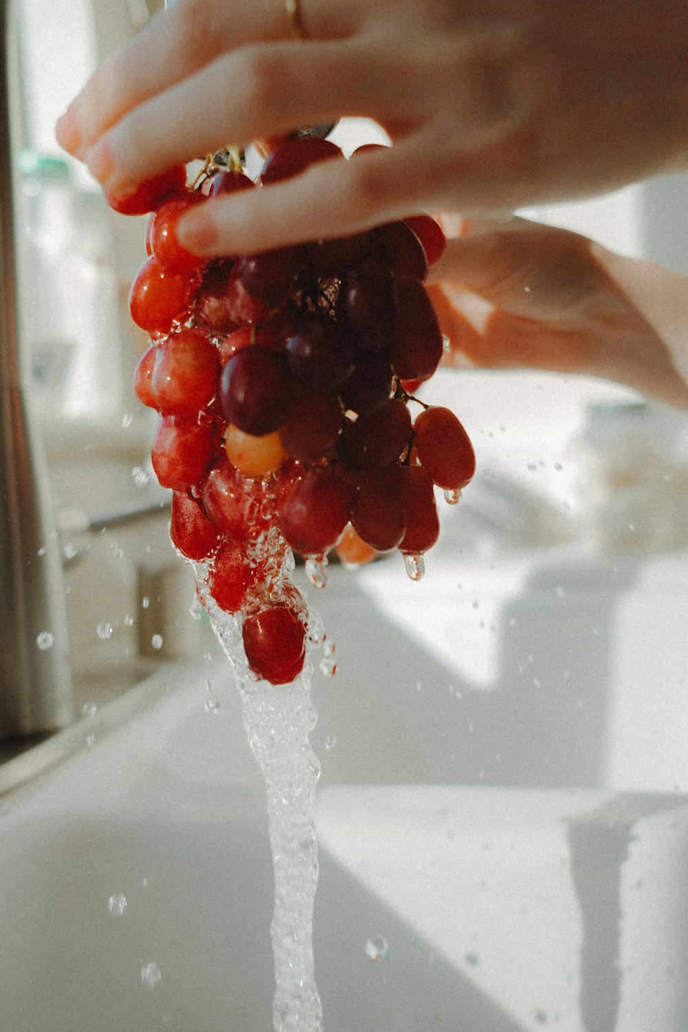 a person is washing grapes in a sink