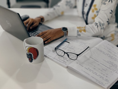 A person working on a laptop with a cup of coffee.