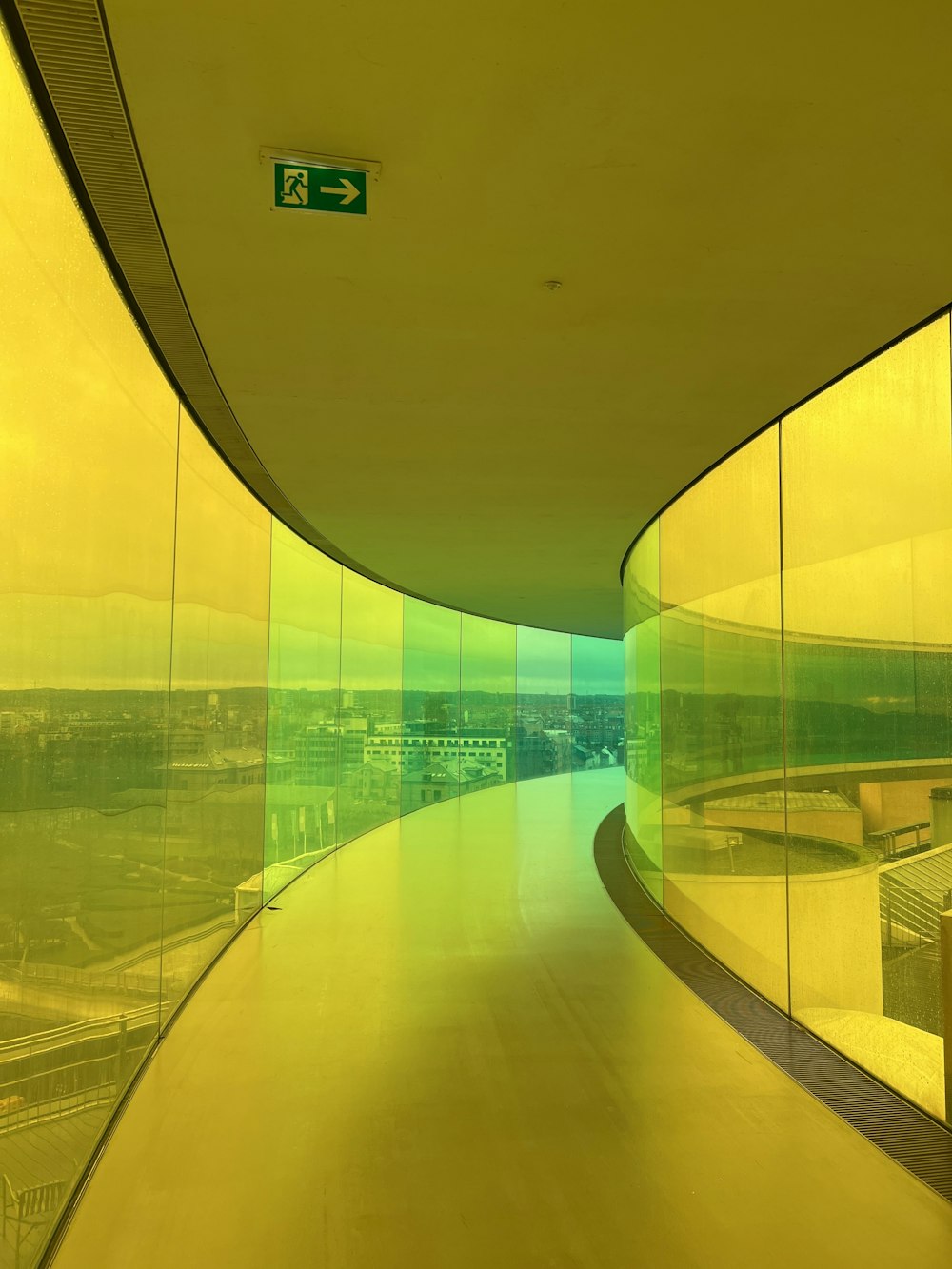 a curved walkway in a building with a view of a city