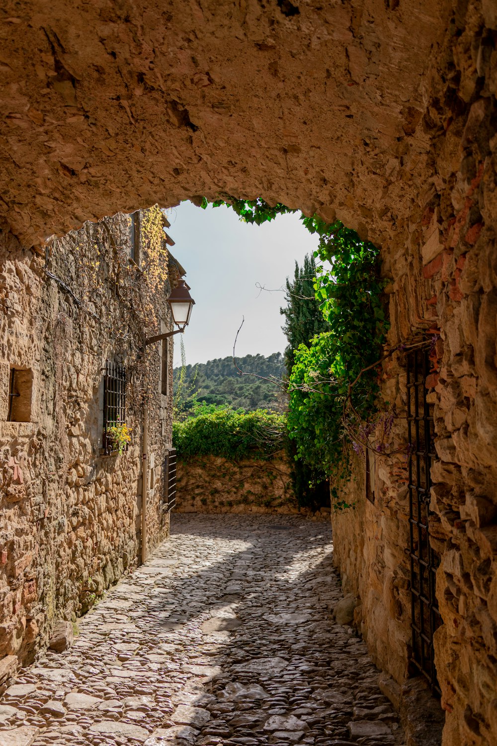 a narrow cobblestone street with a stone building in the background