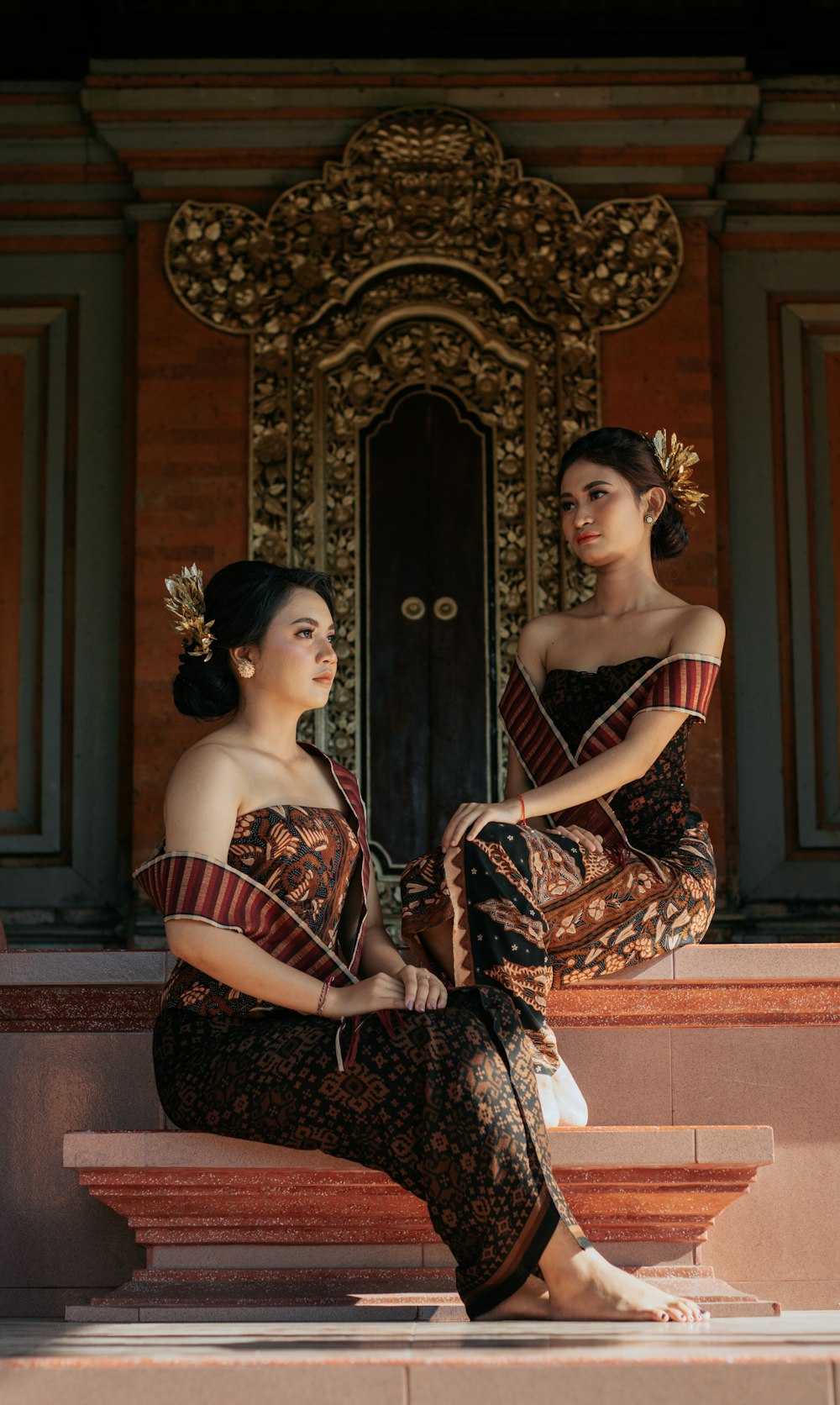 two women sitting on a ledge in front of a door