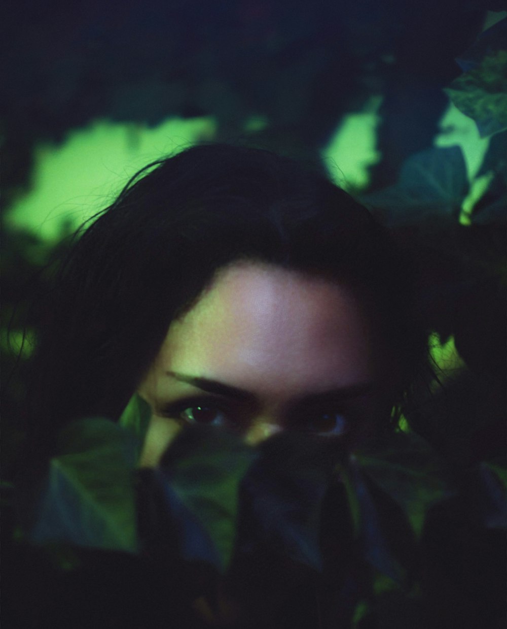 a woman's face is seen through the leaves of a tree
