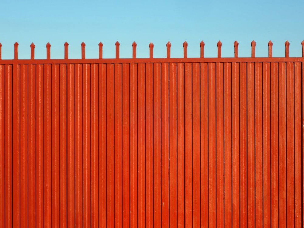 a red fence with a blue sky in the background