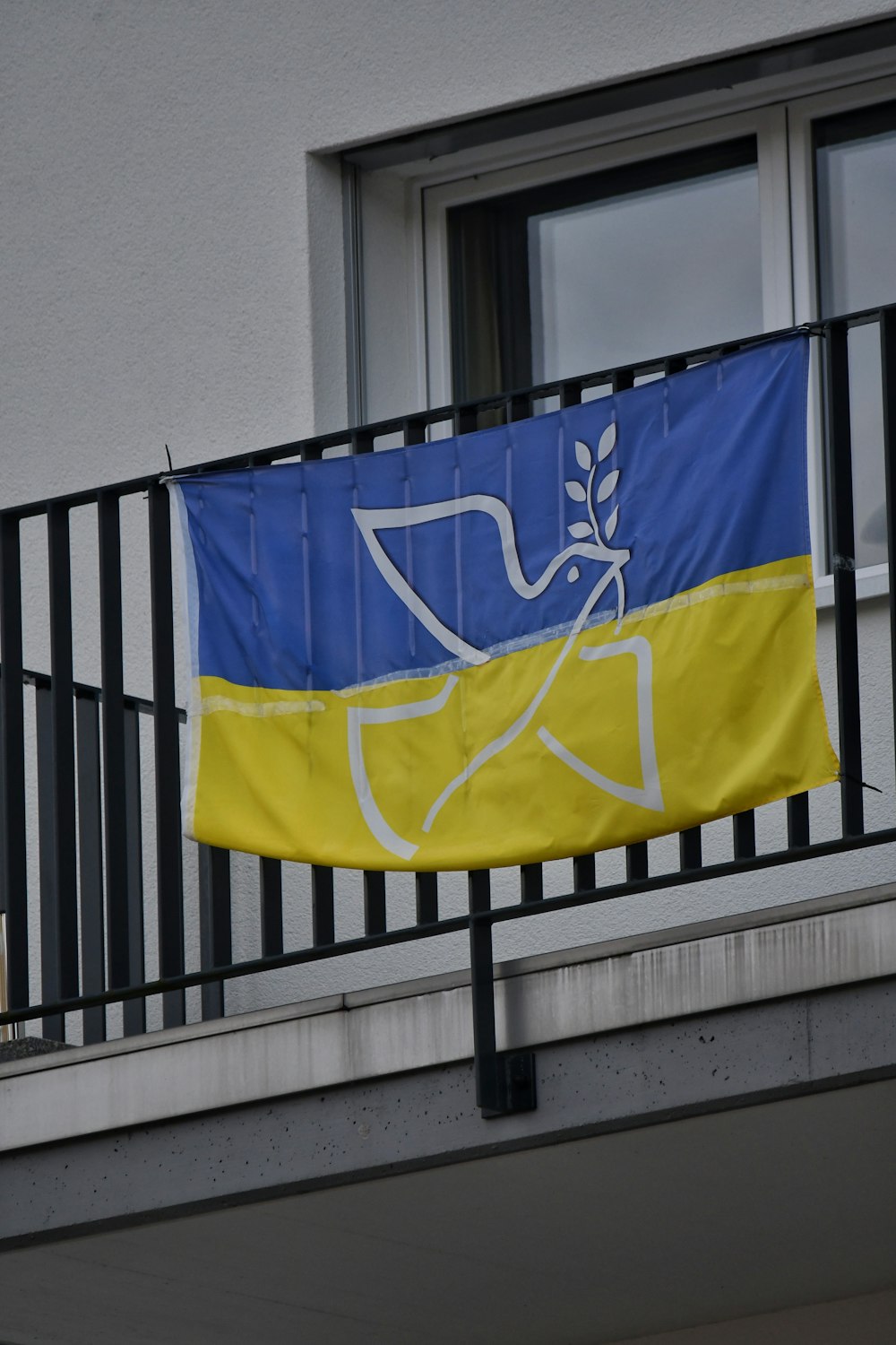 a blue and yellow flag hanging from a balcony