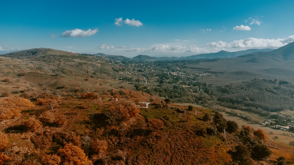 an aerial view of a hilly area with trees and mountains in the background